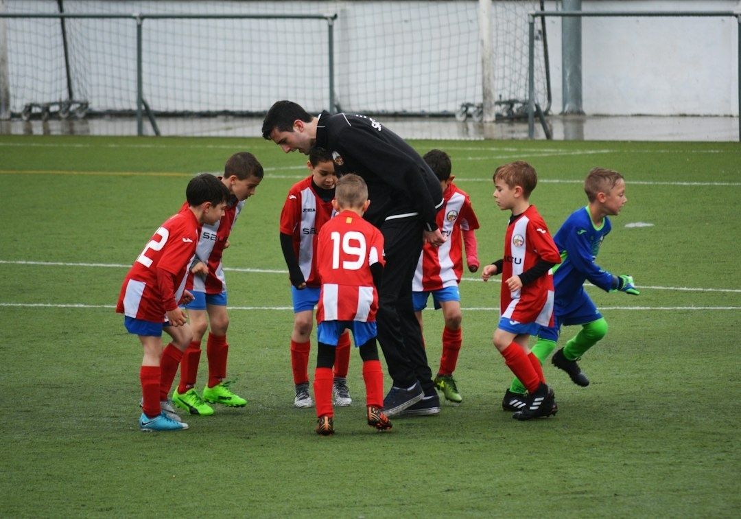 Ungt fotbollslag samlas kring tränaren före match på planen